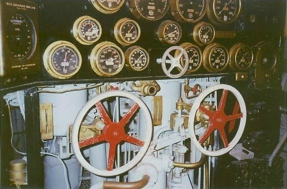 Boiler firing control station with black gauge panel and large red-and-white control handwheels