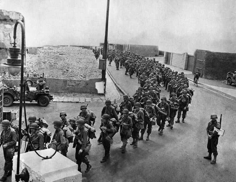 American soldiers march to invasion craft, June 6, 1944