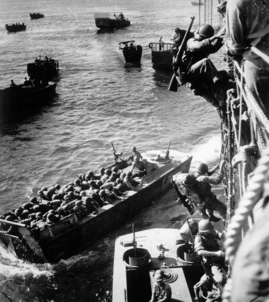 US troops climb over side of Coast Guard transport to enter landing barges at Bougainville November 1943